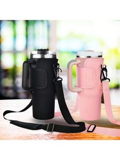 two travel mugs sitting on top of a table next to each other with straps