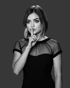 a black and white photo of a woman holding her finger to her lips while looking at the camera