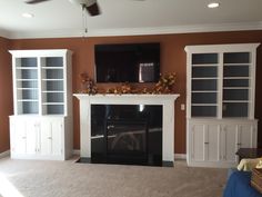 a living room with a fireplace, entertainment center and built - in bookshelves