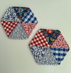 two patchwork coasters sitting on top of a white table next to each other