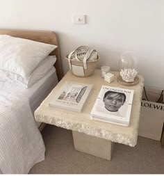 a table with books and magazines on it next to a bed