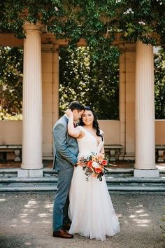 a bride and groom standing in front of some pillars