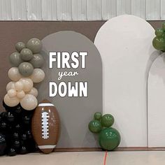 balloons and footballs are on display in front of a sign that says, first year down