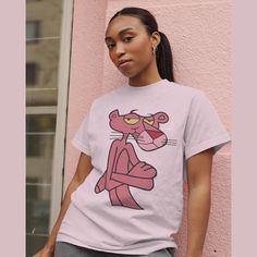 Here it is, the **Pink Panther Shirt** - a perfect blend of retro charm and modern style! Celebrate the timeless elegance of the iconic Pink Panther with this fabulous t-shirt, designed to bring a touch of fun and nostalgia to any wardrobe. This playful and vibrant design makes for an ideal gift, combining cozy comfort with the classic comic appeal of the beloved Pink Panther. Crafted from premium, soft fabric, this shirt offers a luxurious feel while ensuring durability for everyday wear. The h Casual Pink T-shirt For Fan Merchandise, Trendy Pink T-shirt With Character Print, Vintage Pink T-shirt With Graphic Design, Retro Pink T-shirt For Streetwear, Fun Pink Shirt With Cartoon Print, Pink Funny Print T-shirt, Retro Pink T-shirt With Cartoon Print, Pink Graphic Tee With Cartoon Print, Pink Short Sleeve Shirt With Cartoon Print