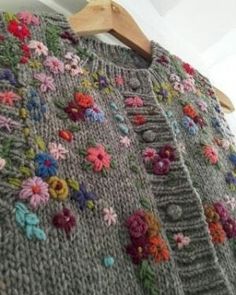 a sweater with flowers on it hanging from a hanger