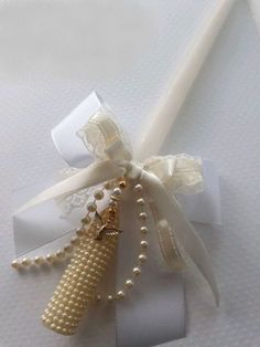 a white ribbon with pearls and a gold bead on it, tied together by a bow