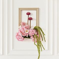 pink flowers are hanging on the white wall