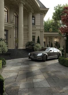 a black car parked in front of a large building with columns on it's sides