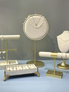 an assortment of jewelry on display in a store window with gold and white accessories around it