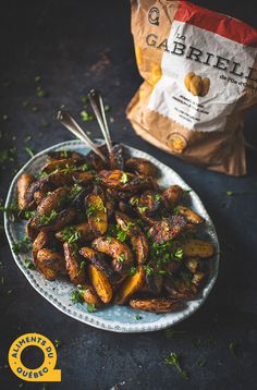 a white plate topped with fried potatoes and garnished with parsley next to a bag of garlic