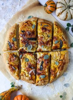 several slices of pizza sitting on top of a cutting board next to mini pumpkins