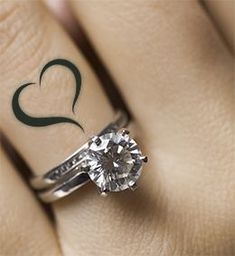 a woman's engagement ring with a heart tattoo on her left hand and a diamond in the middle