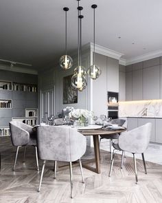 a dining room table with chairs and lights hanging from the ceiling