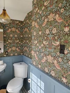 a bathroom with blue walls and floral wallpaper on the walls, along with a toilet and sink