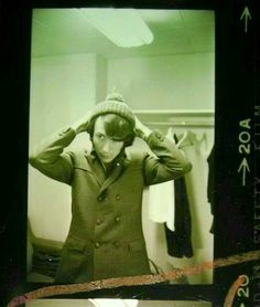 an old photo of a man in a suit holding his hands to his ears and looking at the camera