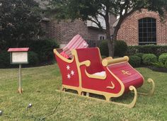 a red and yellow sleigh sitting in the grass next to a mailbox