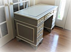 an office desk with drawers in front of a door and glass windows on the wall