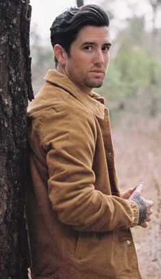 a man leaning against a tree in the woods