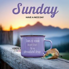 a purple coffee mug sitting on top of a wooden table next to a leaf and mountains