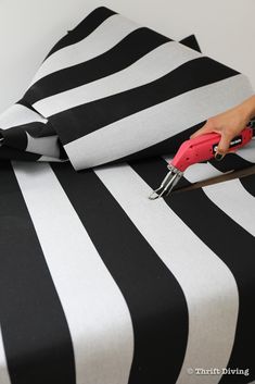 a person is using a pair of pliers to cut the black and white striped fabric