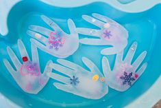 four plastic hand prints in a blue bowl filled with water and snowflakes