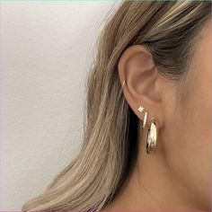 a woman with blonde hair wearing two gold hoop earrings and a star earring on her left ear