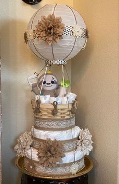 a three tiered diaper cake sitting on top of a wooden table next to a clock