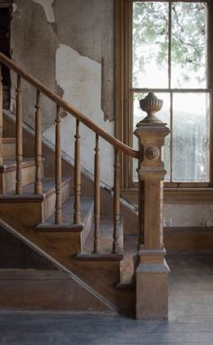 an old building with some stairs and a window in it's center, next to a set of wooden handrails