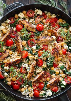 a skillet filled with chicken, tomatoes and chickpeas