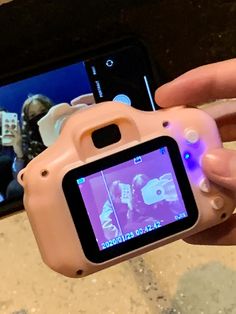 a person holding up a pink camera to take a picture with their cell phone in front of them