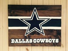 a wooden sign with the word dallas cowboys painted on it and a star in the center