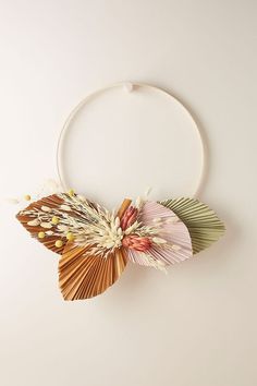 an image of a flower decoration hanging on a white circle wall ornament in the shape of a fan