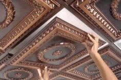 a person is painting the ceiling in a room with gold trimmings on it