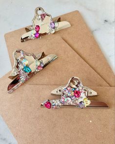 three different types of hair clips sitting on top of a piece of brown paper next to each other