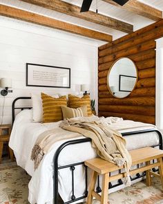 a bedroom with wood paneling and white bedding, wooden stools and mirror on the wall