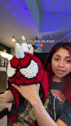 a woman holding up a knitted red and white stuffed animal in front of her face