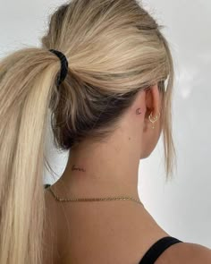 the back of a woman's head with a tattoo on her left side behind her ear