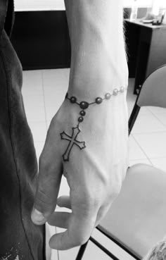 a person with a cross tattoo on their hand and chain around the wrist is shown