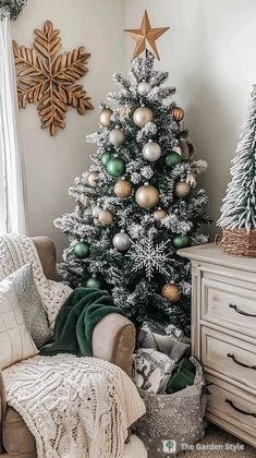 a white christmas tree with green and gold ornaments in a living room decorated for the holidays