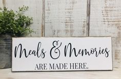 a wooden sign that says meals and memories are made here next to a potted plant