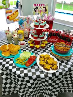 a table topped with lots of food next to a checkered tablecloth covered table