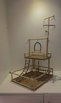 a sculpture made out of wood and beads on top of a white table with drawers