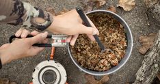 a person is cooking food in a pot on the ground next to an open stove