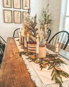 a wooden table topped with lots of candles and greenery next to a potted plant