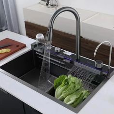 a kitchen sink filled with lettuce next to a cutting board