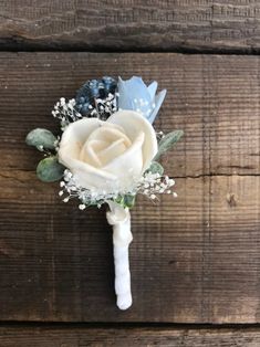 a boutonniere with flowers and baby's breath attached to it on a wooden surface