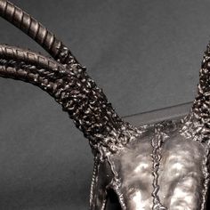 an animal's head is made out of metal and has long, curled horns