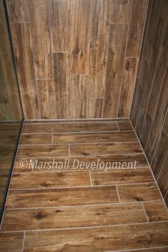 a bathroom with wood flooring and tile on the shower wall is seen in this image