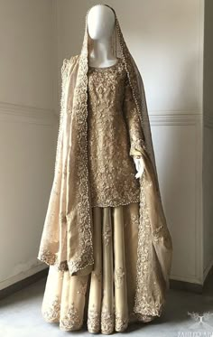 a mannequin dressed in an elaborate gold gown and shawl, with long sleeves