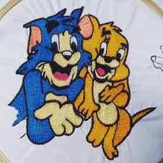 two cartoon characters are hugging each other in front of a white background with embroidery on it